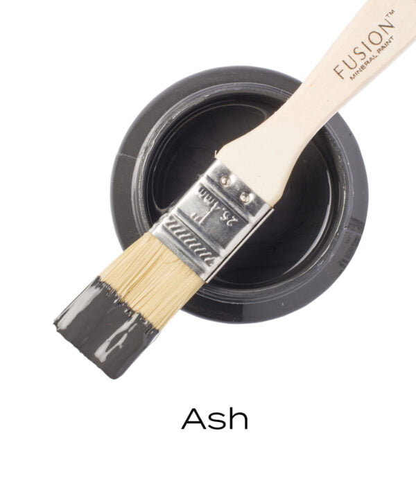 An angled brush that has been dipped in, and then placed on top of an open pint of Ash Fusion mineral paint to indicate the colour.