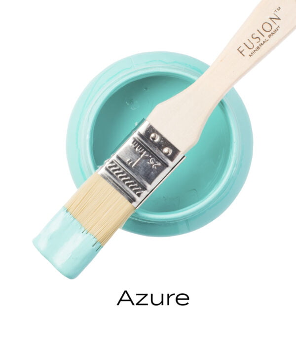 An angled brush that has been dipped in, and then placed on top of an open pint of Azure Fusion mineral paint to indicate the colour.