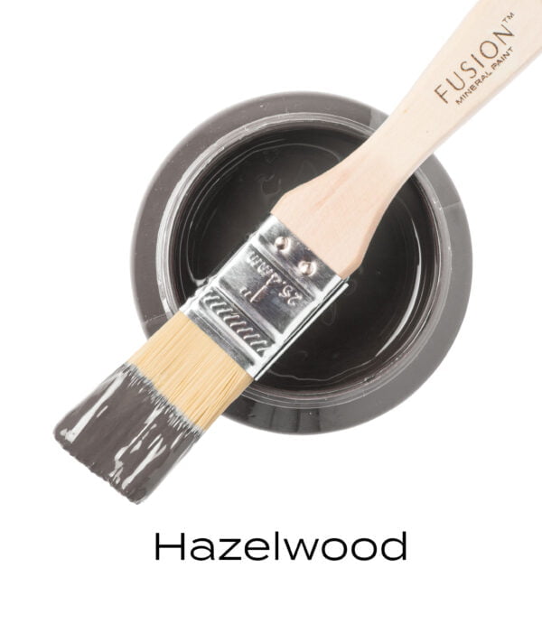 An angled brush that has been dipped in, and then placed on top of an open pint of Hazelwood Fusion mineral paint to indicate the colour.