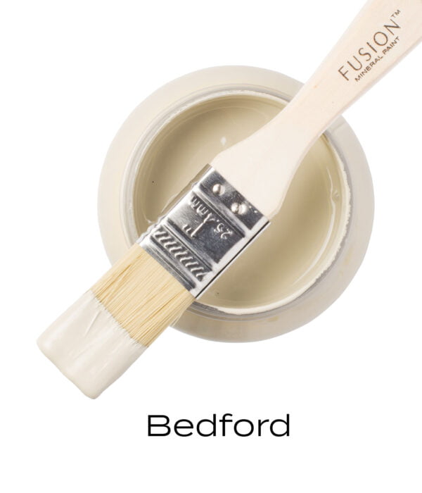 An angled brush that has been dipped in, and then placed on top of an open pint of Bedford Fusion mineral paint to indicate the colour.