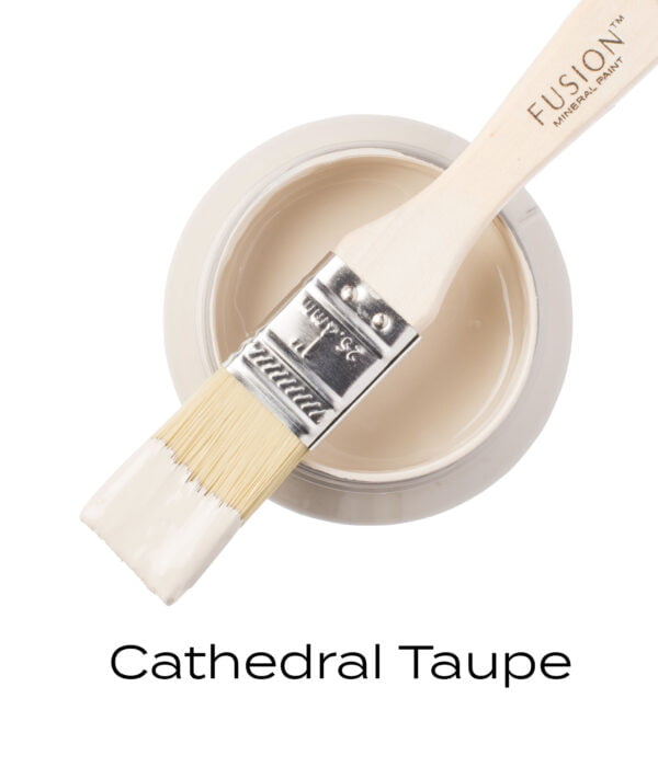 An angled brush that has been dipped in, and then placed on top of an open pint of Cathedral Taupe Fusion mineral paint to indicate the colour.