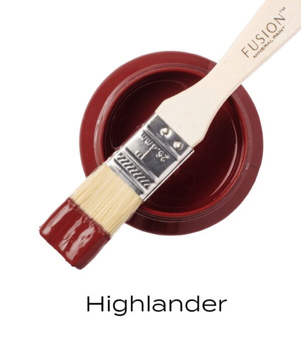 An angled brush that has been dipped in, and then placed on top of an open pint of Highlander Fusion mineral paint to indicate the colour.