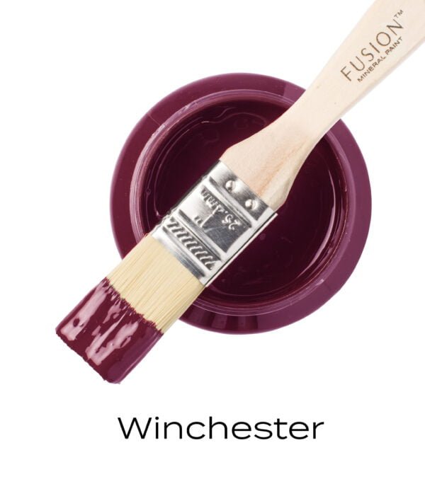 An angled brush that has been dipped in, and then placed on top of an open pint of Winchester Fusion mineral paint to indicate the colour.